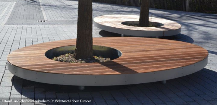 Runde Parkbank aus Holz und Metall um einen Baum, Modell Saturn von FreiraumObjekte Ney GmbH.